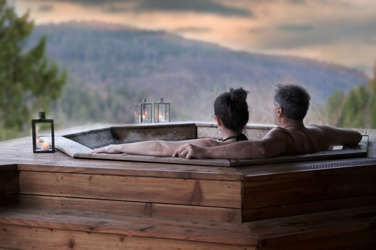 man and woman sitting in hot tub outdoor looking off to mountains