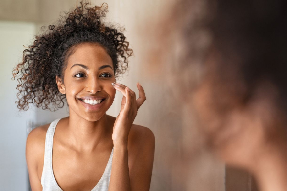 young black woman putting lotion on