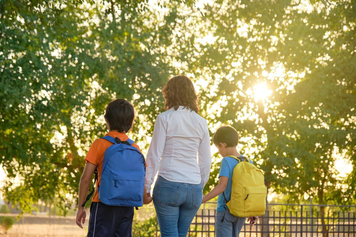 Mother walking with two sons wearing back packs